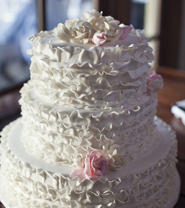 White Ruffle Wedding Cake with Pink Flower Accents